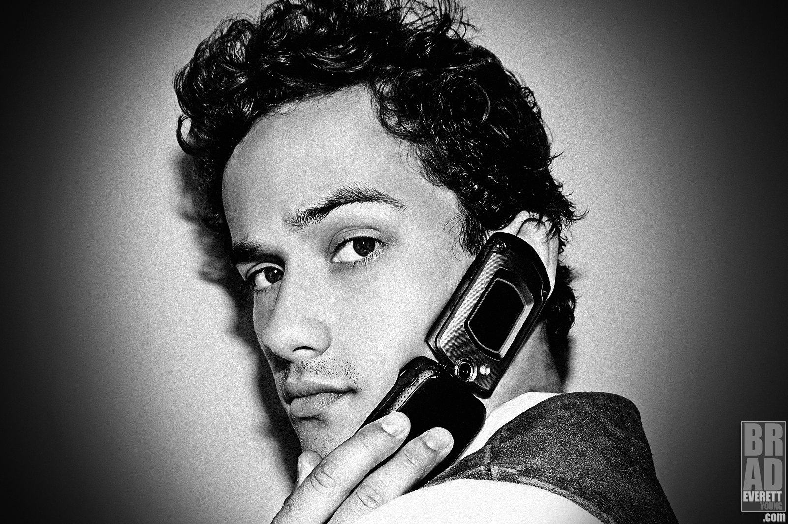 close-up black-and-white photo of Eli Brown holding a flip phone